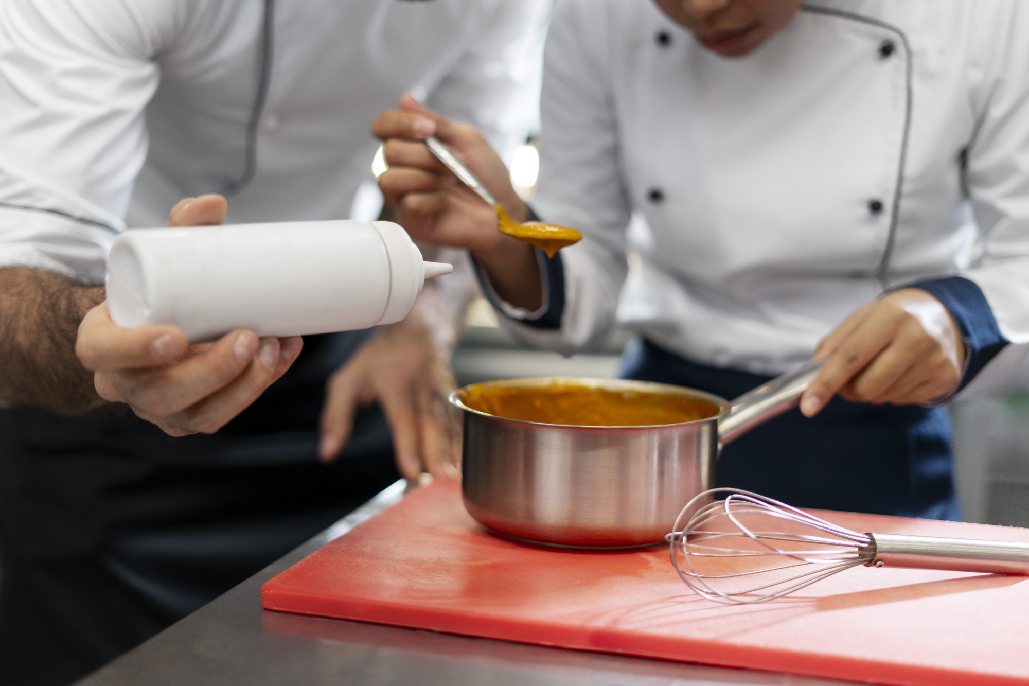 Chef coaching student on sauce technique